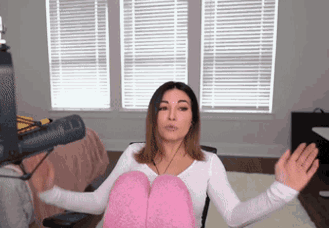 a woman in a white shirt and pink socks is sitting in front of a microphone