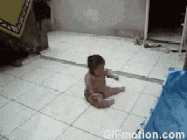 a baby in a diaper is sitting on a tiled floor next to a gif motion.com sign