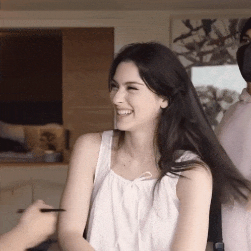 a woman wearing a white tank top is smiling
