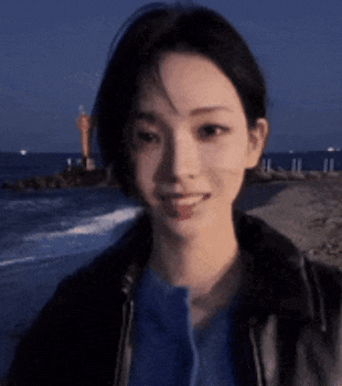 a close up of a woman standing on a beach with the ocean in the background .