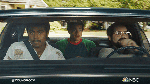 three men are sitting in a car with the nbc logo visible