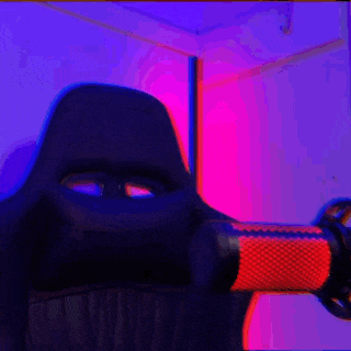 a person is sitting in front of a microphone in a room with purple and pink lights .
