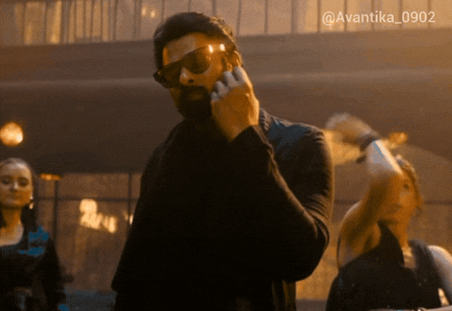 a man wearing sunglasses is talking on a cell phone with the hashtag avantika_0902 above him