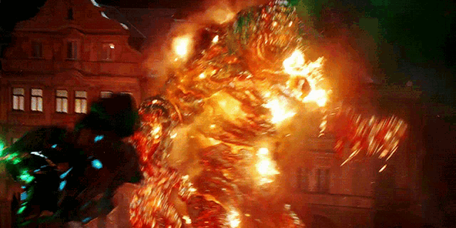 a large fireball is coming out of a building at night