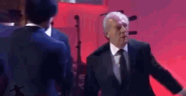 a man in a suit and tie is standing in front of a red background