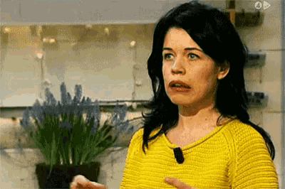 a woman wearing a yellow sweater is making a funny face .
