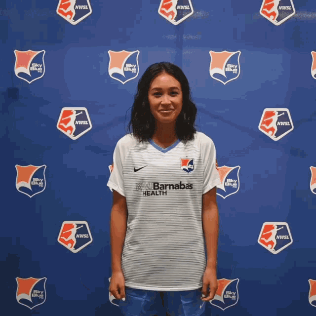 a woman stands in front of a blue backdrop that says nwwsl
