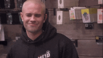 a man wearing a black hoodie with the word mctd on it is smiling .