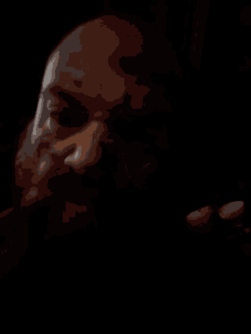 a close up of a man 's face in the dark with a beard .