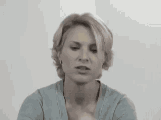 a woman in a blue sweater is holding a banana in her hand and making a funny face .