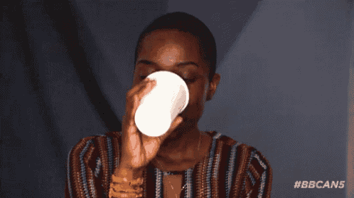 a woman is drinking from a white cup with the bbcan5 logo in the corner