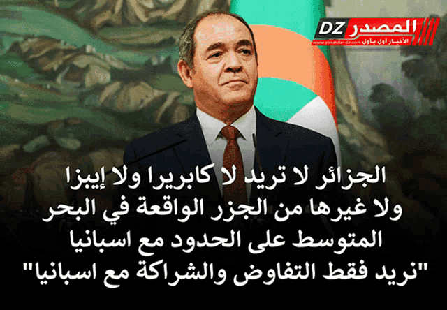 a man in a suit and tie stands in front of a flag with dz on the bottom