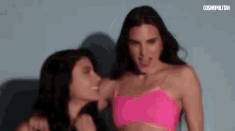 two women in pink bikinis are standing next to each other and making funny faces .