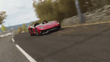 a red sports car driving down a road with trees in the background