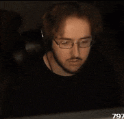 a man wearing glasses and headphones is sitting in front of a computer with the number 797 on the screen