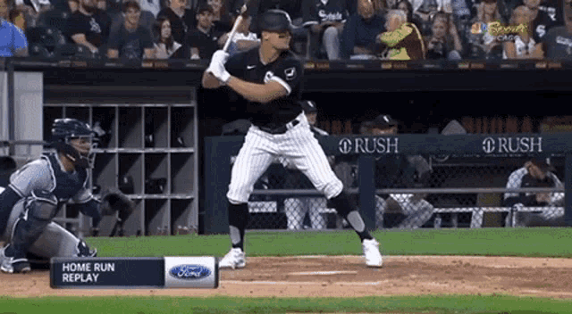 a baseball player getting ready to swing at a pitch with a home run replay sign in front of him