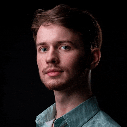 a man with a beard and a blue shirt looks at the camera