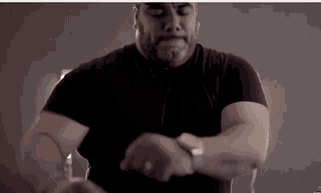 a man with a beard wearing a black shirt looks at his watch