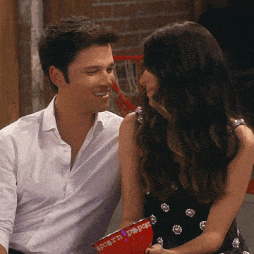 a man and a woman are looking at each other and the woman is holding a bowl that says popcorn