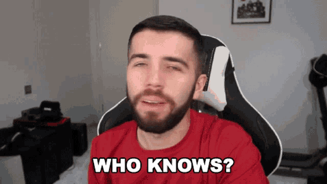a man with a beard is sitting in a chair and asking who knows