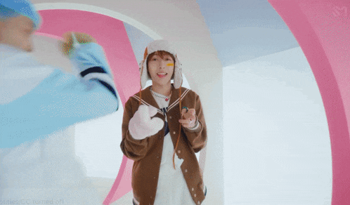 a person wearing a hat and gloves is standing in front of a pink and white circle
