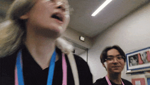 a woman with glasses and a pink lanyard around her neck stands next to a man with glasses and a pink lanyard around his neck