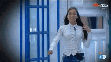 a woman in a white shirt and jeans is dancing in front of a blue prison cell .