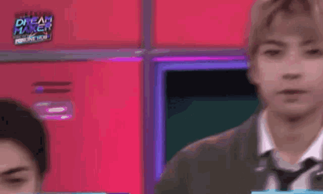 a man in a suit and tie is standing in front of a pink wall in a room .