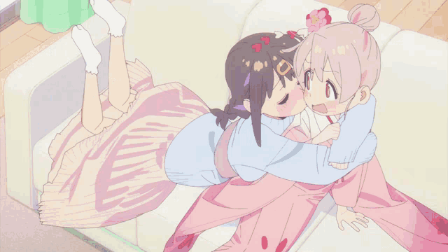 two girls are hugging each other on a couch and one has a flower in her hair