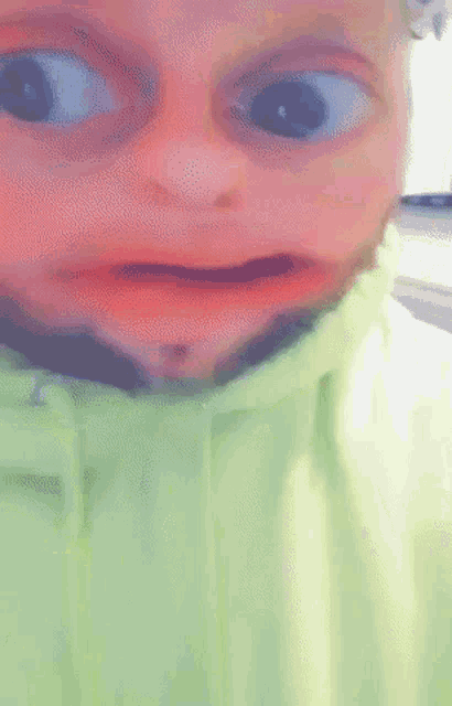 a close up of a person 's face with a green jacket