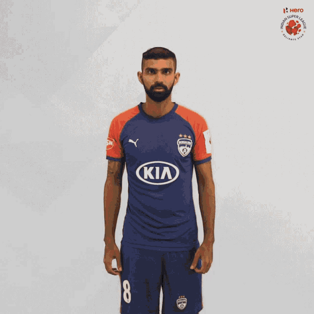 a man with a beard wears a blue and orange kia jersey