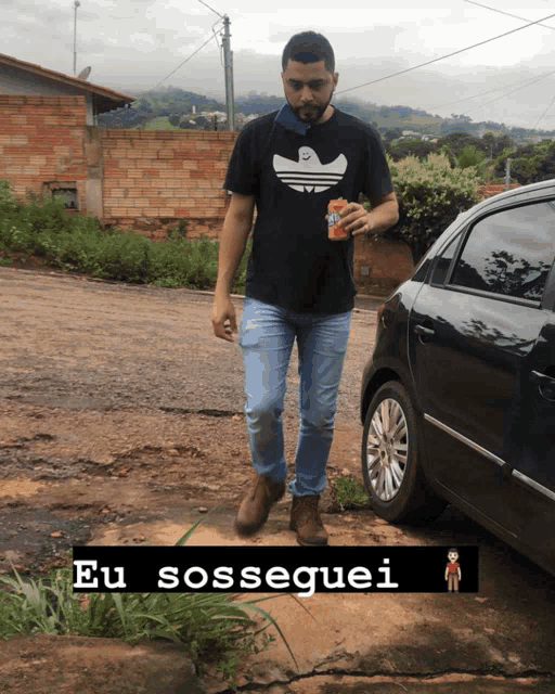 a man in a black adidas shirt is walking down the street