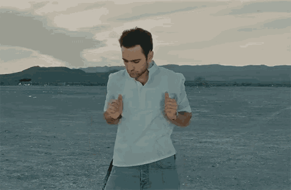 a man in a white shirt and jeans is dancing in a desert