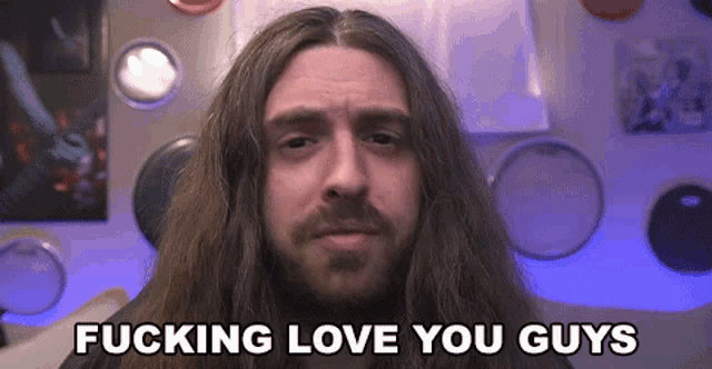 a man with long hair and a beard is sitting in front of a drum set .