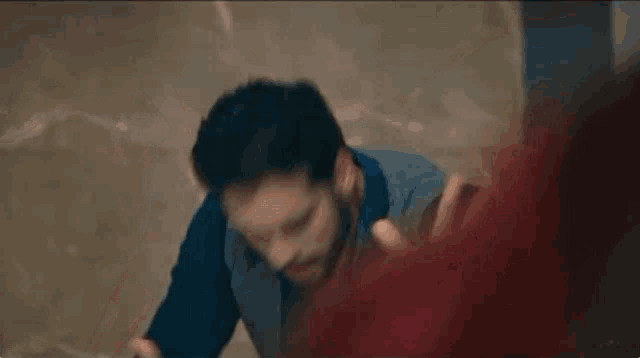 a man with a beard is standing in a dark room with a red smoke coming out of his mouth .
