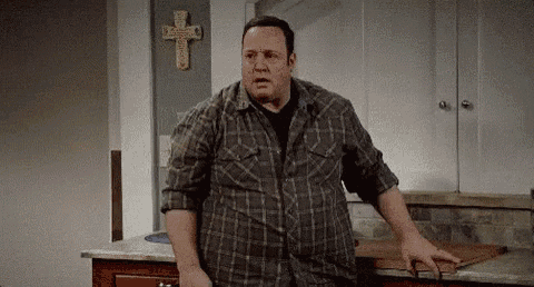 a man in a plaid shirt is standing in front of a cross in a kitchen .