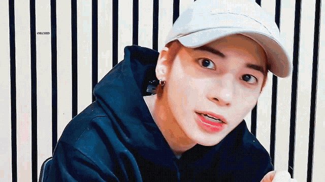 a young man wearing a baseball cap and a black hoodie .