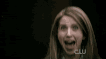 a woman is making a funny face with her hands in her mouth .