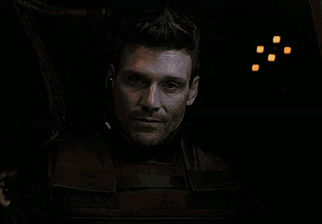 a close up of a man 's face in a dark room with red lights behind him