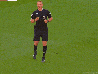 a soccer referee wearing a nike shirt stands on a field