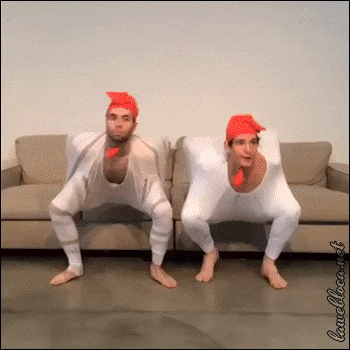 two men in chicken costumes are squatting on a couch ..