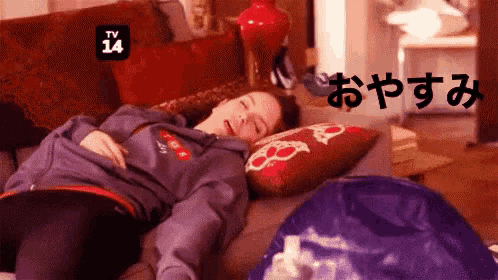 a woman is sleeping on a couch with a tv 14 logo above her head