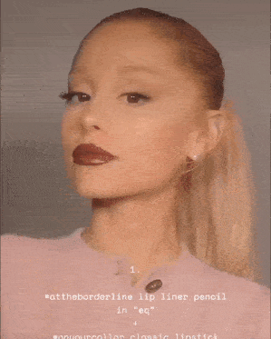 a woman is holding a lip gloss in her hands and making a face