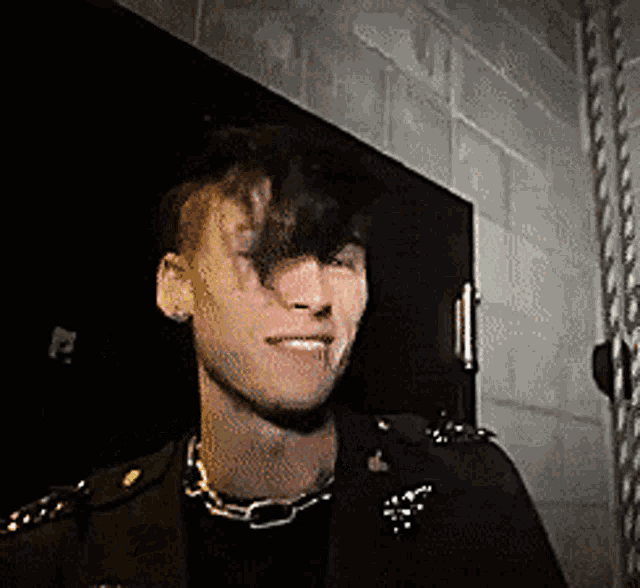 a young man wearing a black jacket and a chain around his neck