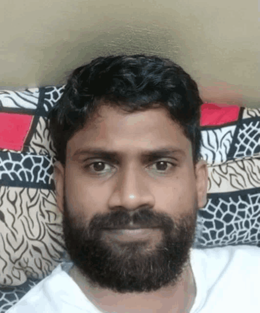a man with a beard is laying on a colorful blanket