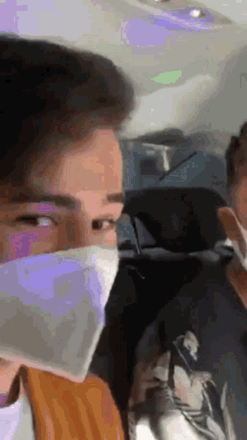 a man wearing a face mask is sitting in the back seat of a car