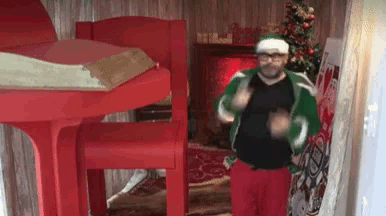 a man in a santa hat is dancing in front of a fireplace