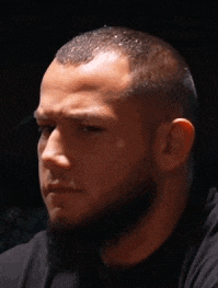 a man with a beard is wearing a black shirt and looking at the camera