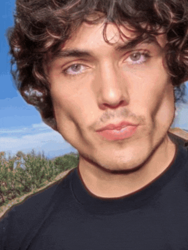 a close up of a man 's face with a blue sky behind him