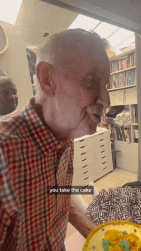 a man in a plaid shirt is standing in front of a cake with a caption that says you take the cake